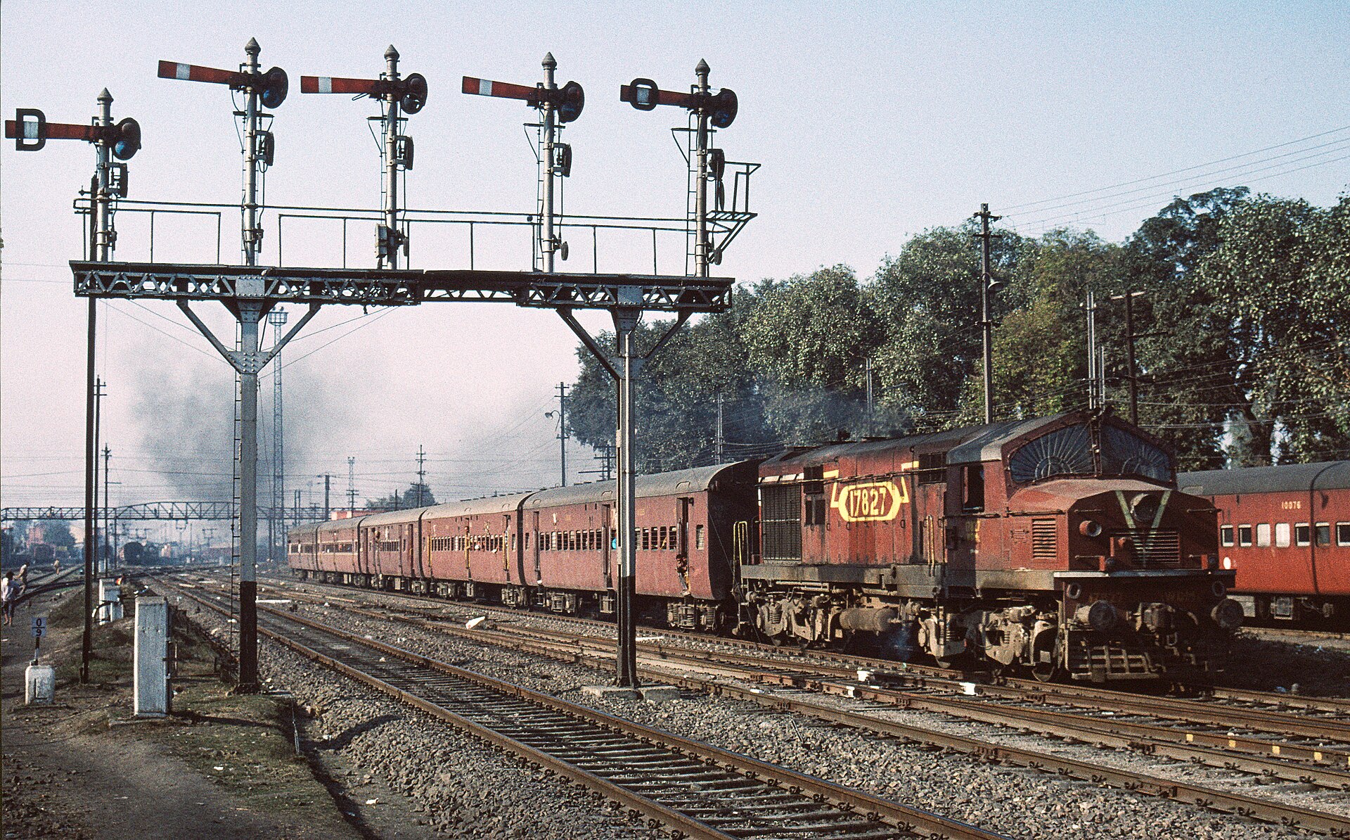 A diesel-hauled passenger train passing a gantry of semaphore signals at Jalandhar, Punjab