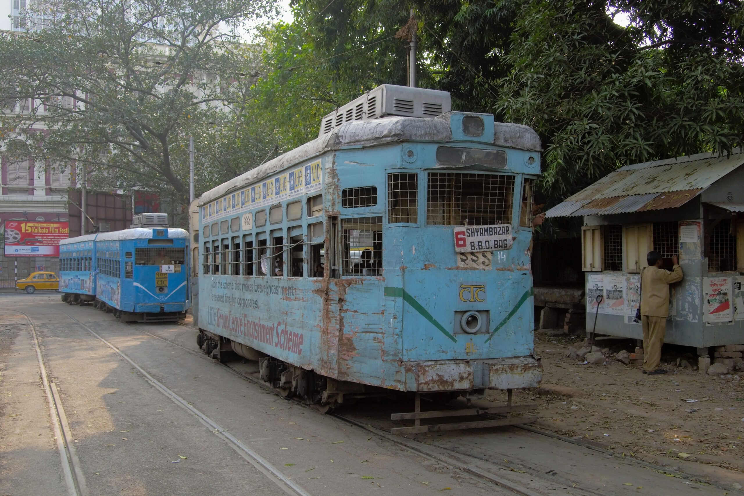 Two blue-and-white Kolkata trams on a city street