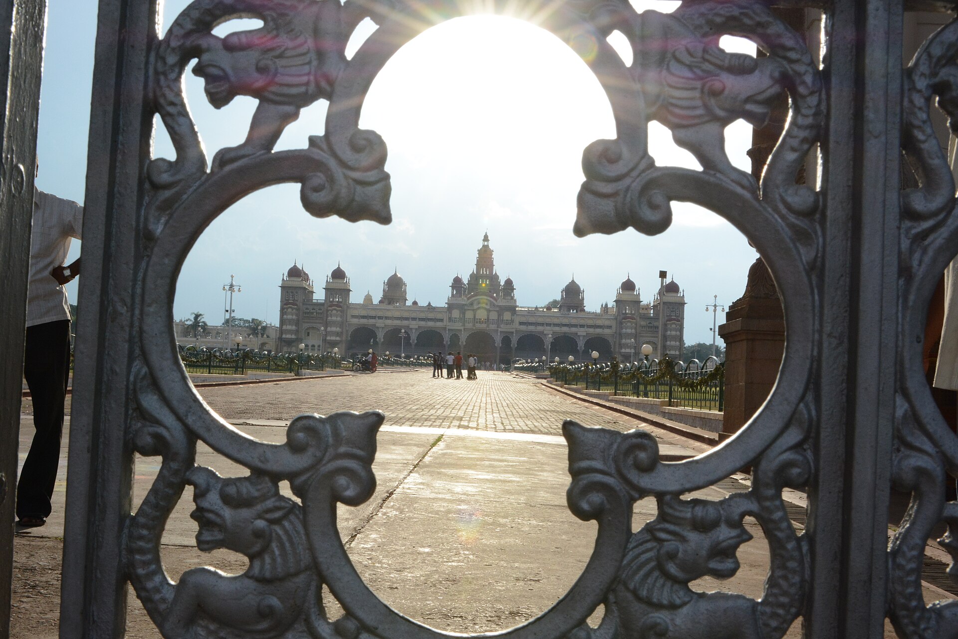 Mysore Palace framed through an ornate wrought-iron gate at sunset
