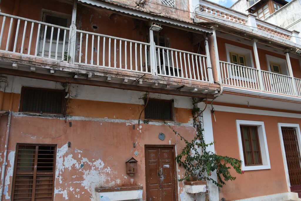 Weathered colonial facade with white balustraded balconies in Pondicherry's French Quarter
