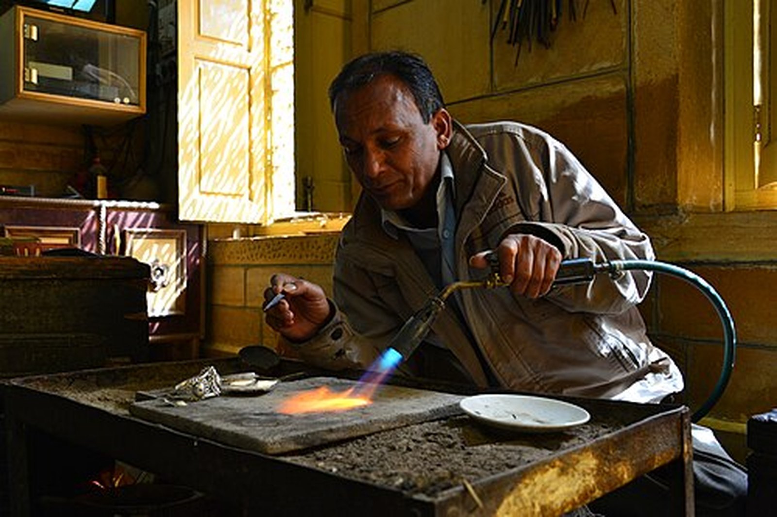 Rajasthani silversmith working metal with a torch at his bench