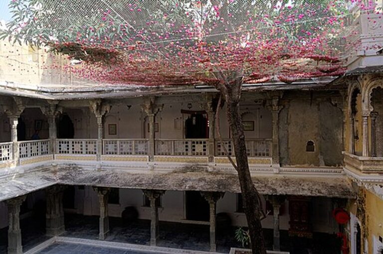 Central courtyard of Bagore Ki Haveli with arcaded galleries and a flowering tree, Udaipur