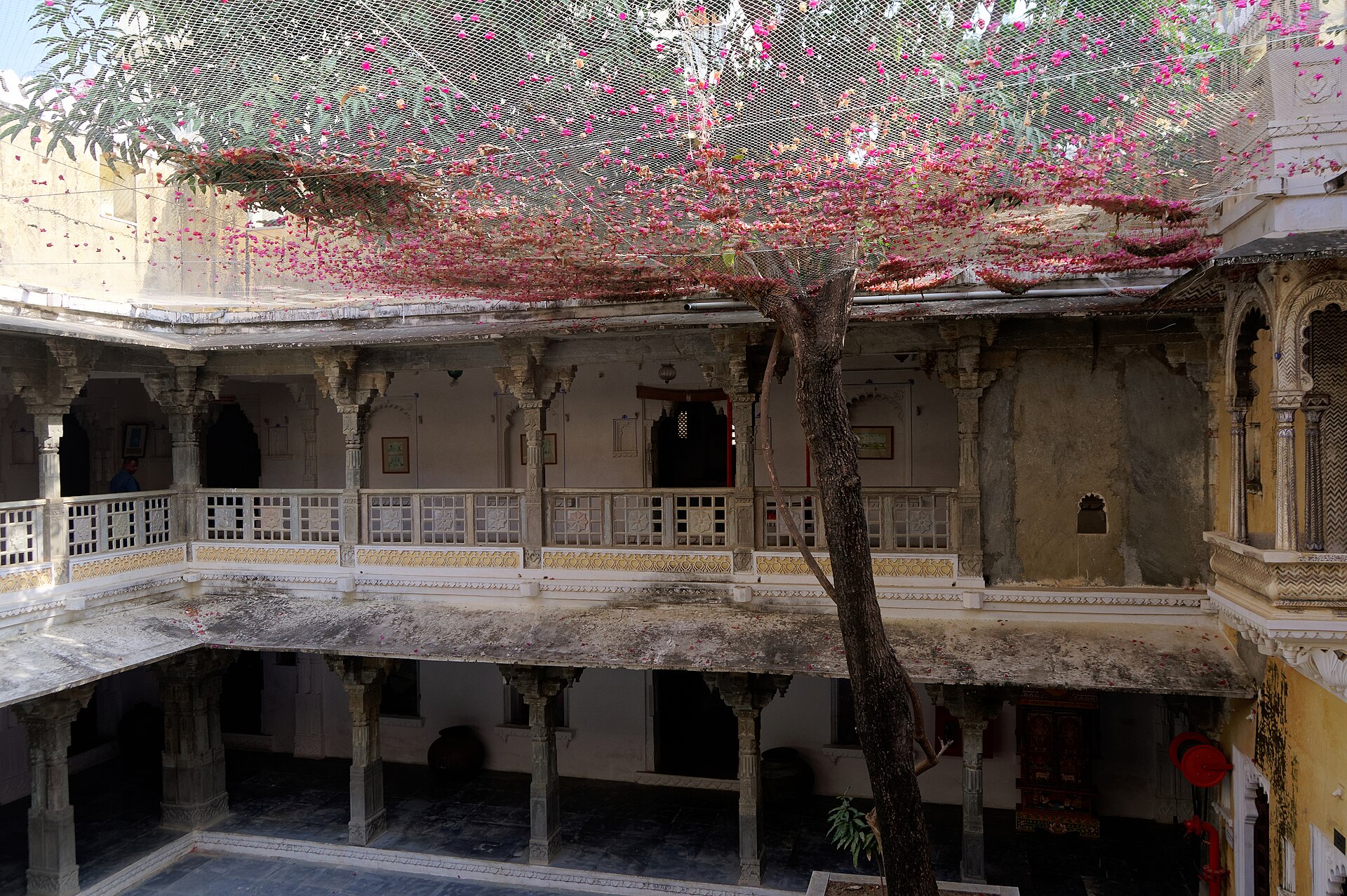 Courtyard of Bagore Ki Haveli in Udaipur with a flowering tree and carved balconies