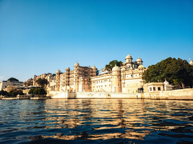 City Palace Udaipur rising above the shimmering waters of Lake Pichola on a clear day, Mewar, Rajasthan