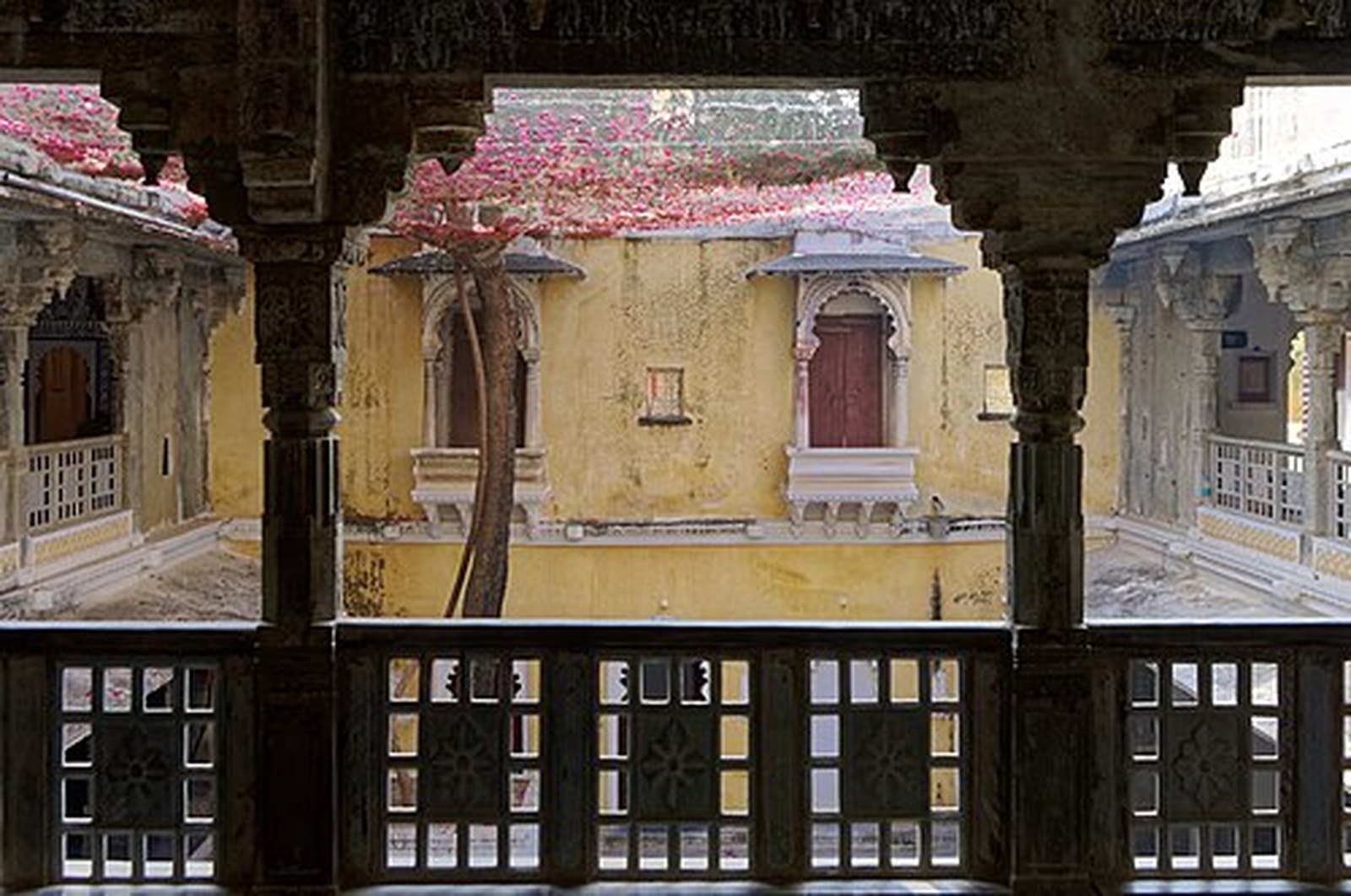Haveli courtyard framed by carved wooden pillars and lattice railings in Bagore Ki Haveli