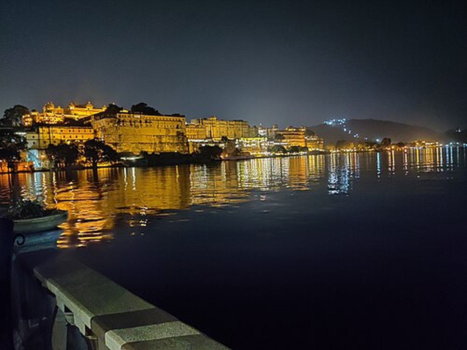 Night lights of Udaipur shimmering across the still surface of Lake Pichola
