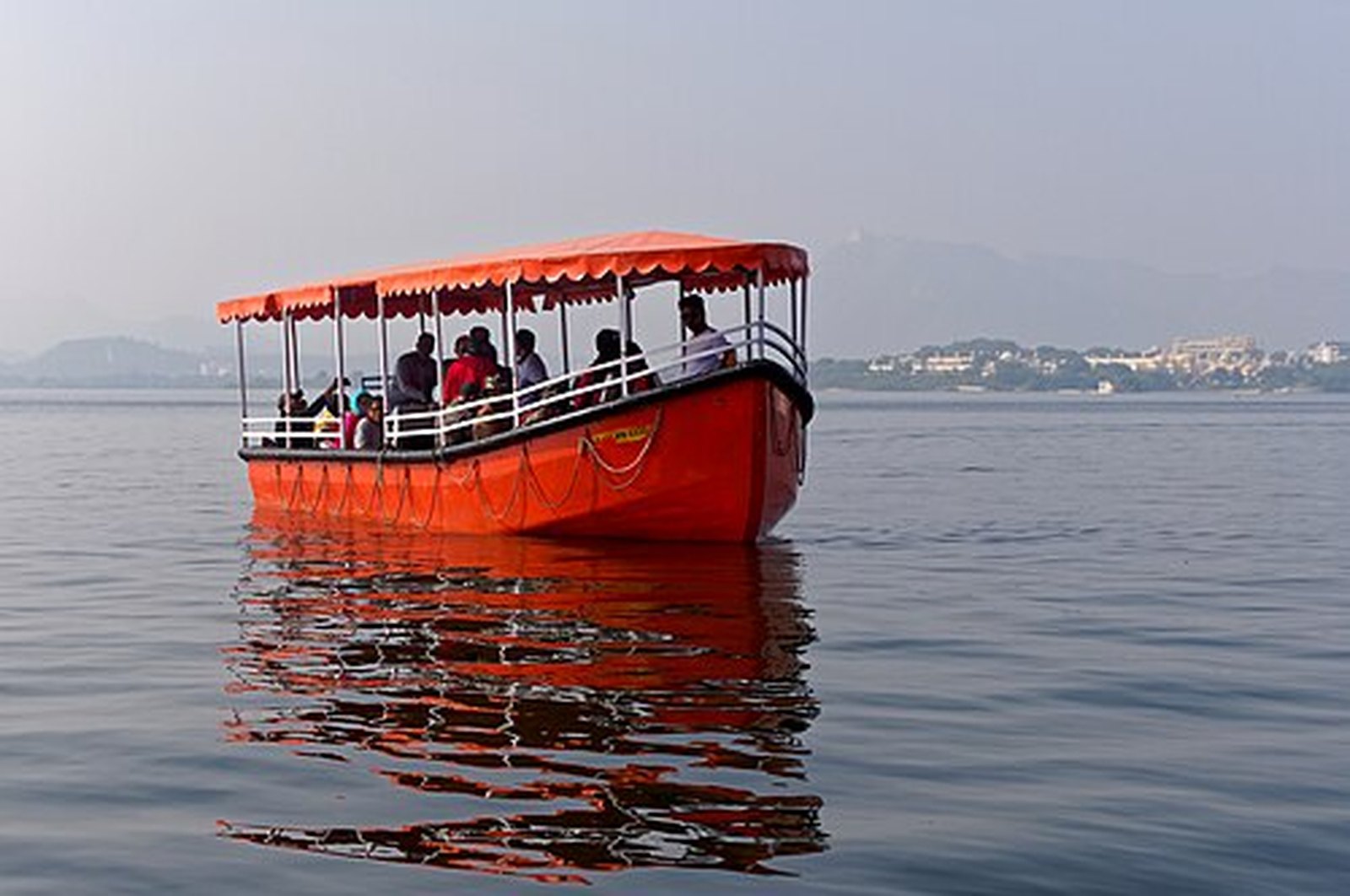 Red tourist boat gliding across Lake Pichola in Udaipur