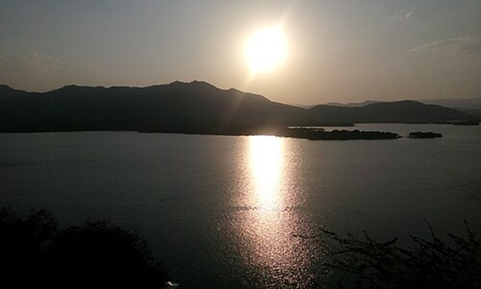 Sun dipping behind the Aravalli ridges over Lake Pichola, Udaipur
